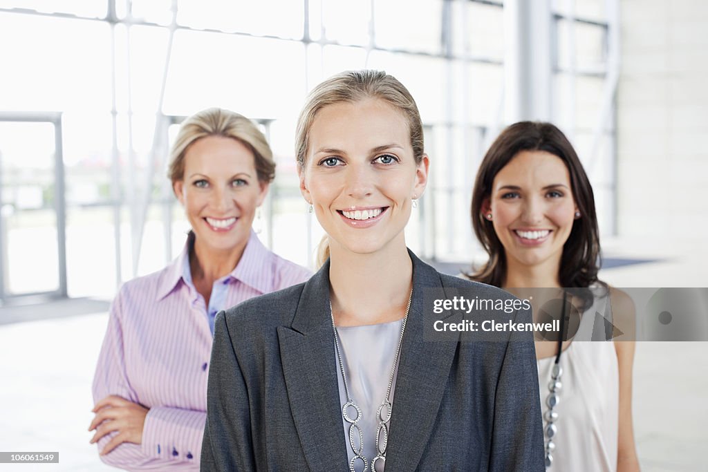 Confident businesswoman with co-workers smiling, portrait