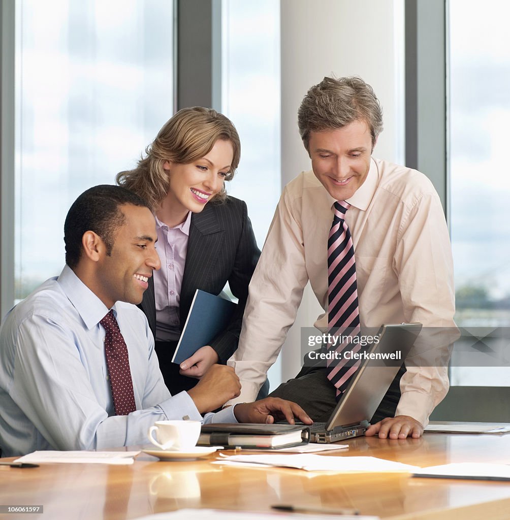 Three business executives using laptop at office desk