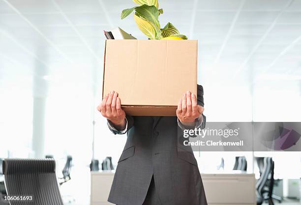 businessman carrying cardboard box of office items - moving office stock pictures, royalty-free photos & images