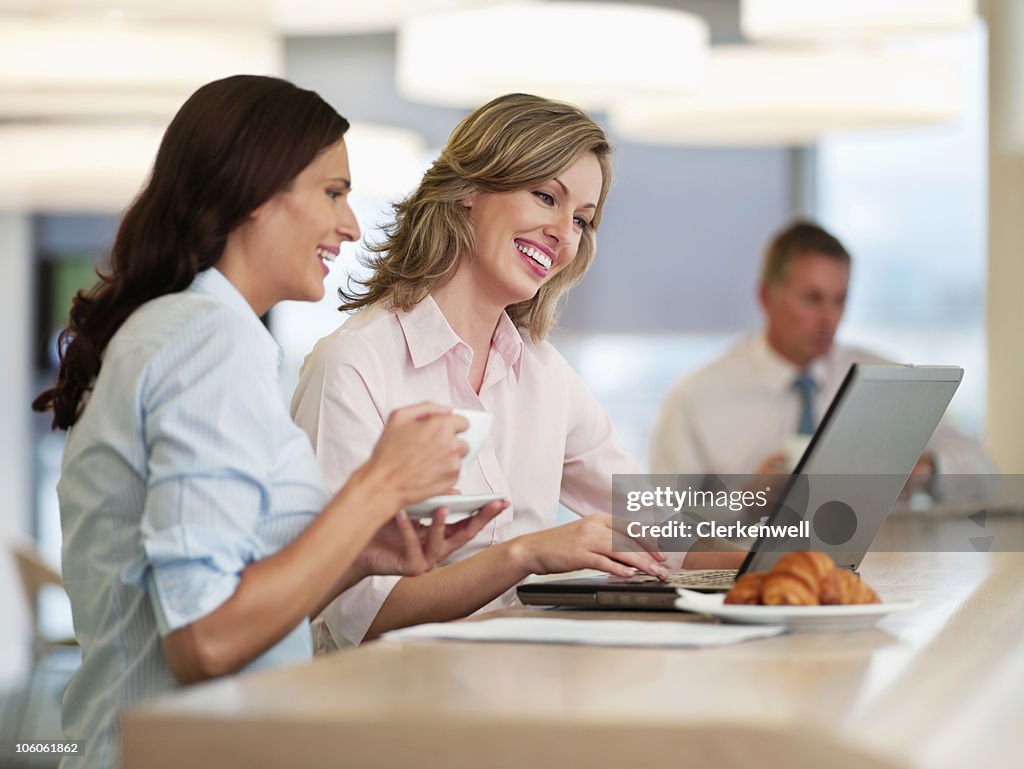 Business people using laptop with male colleague in the background