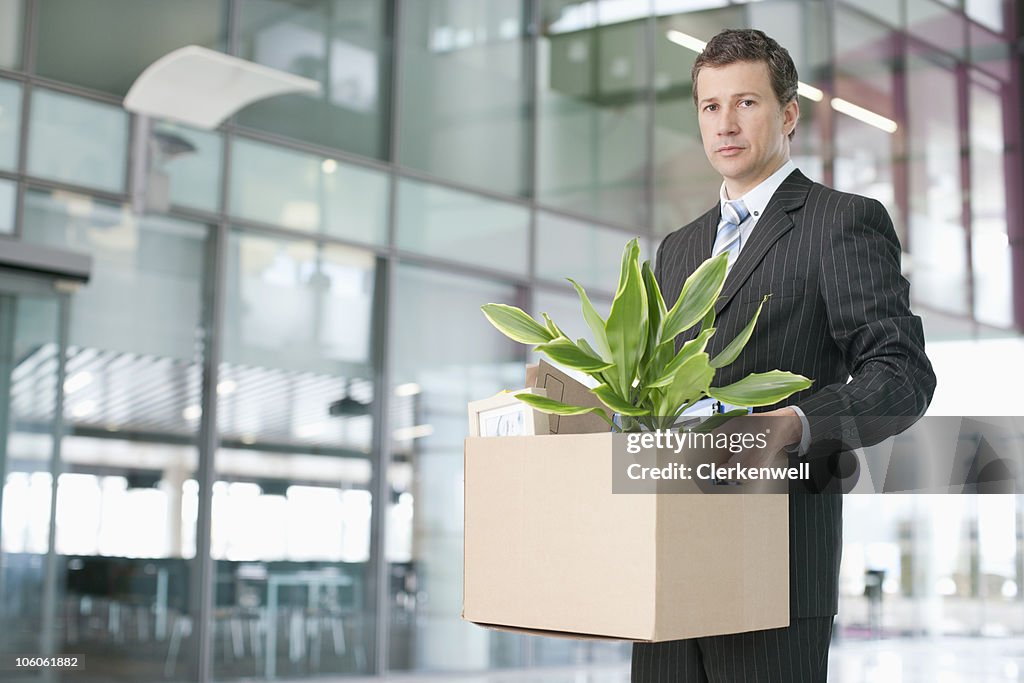 Portrait of a serious looking business executive carrying a cardboard box