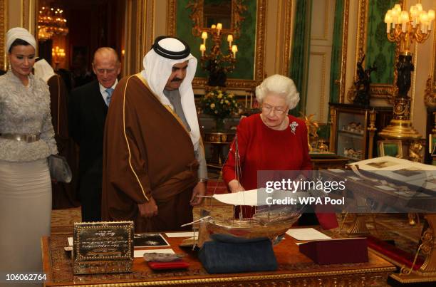 Queen Elizabeth II shows the Emir of Qatar Sheikh Hamad bin Khalifa al-Thani around exhibits with one of his three wives, Sheikha Mozah bint Nasser...