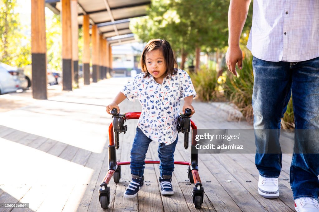 Hispanic Boy with Down's Syndrome Using Walker with Dad