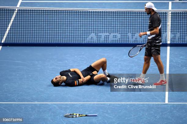 Marcelo Melo of Brazil falls to the floor after being hit by a tennis ball as partner Lukasz Kubot of Poland reacts during Day Two of the Nitto ATP...