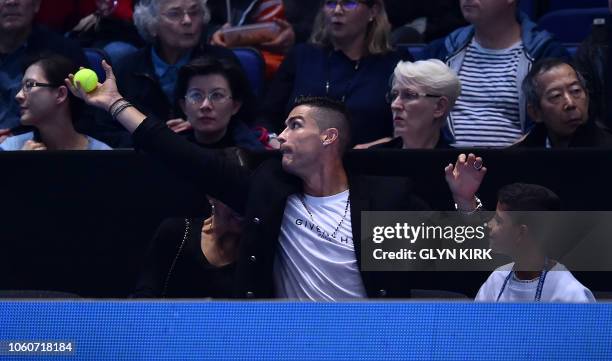 Juventus' Portuguese forward Cristiano Ronaldo catches a stray ball as Serbia's Novak Djokovic plays against US player John Isner in their men's...