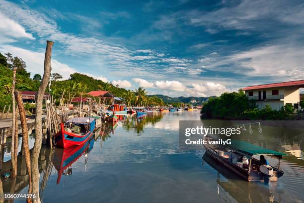 A local fisherman goes out on a boat from boats park to the sea for fishing. Traditional colorful asian fishing boats in fishing village. Langkawi island, Malaysia.