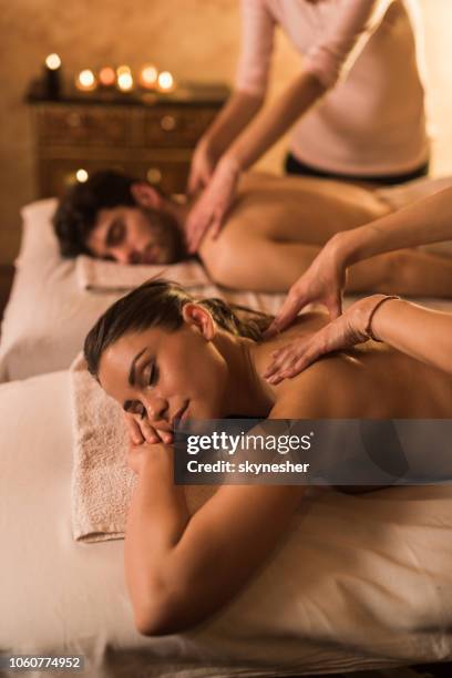 young couple having back massage during their spa treatment. - massage couple stock pictures, royalty-free photos & images