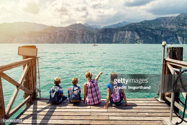 familie zittend op de pier in malcesine en genieten van uitzicht op het gardameer - bergsteiger stockfoto's en -beelden