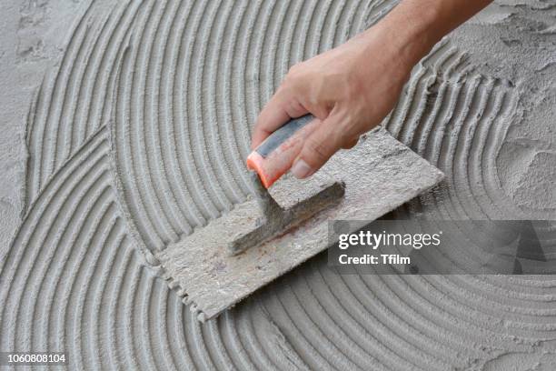 hand on be bound with cement , do cement work, apply cement (over a surface) - concrete building stockfoto's en -beelden