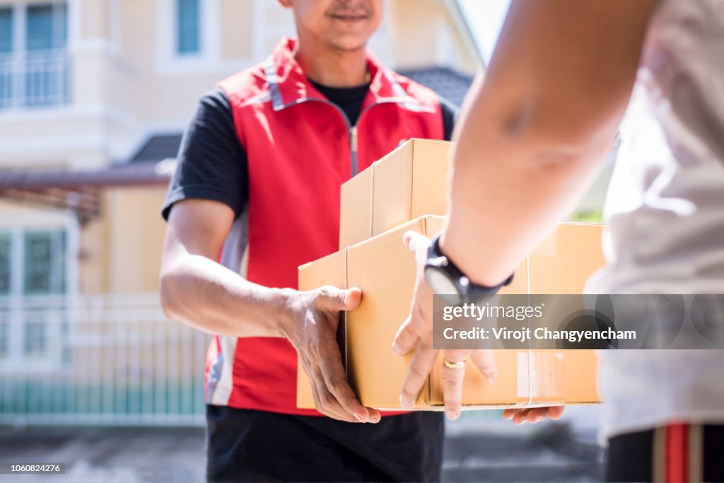 Parcel delivery man of a package through a service and customer hand accepting a delivery of boxes from delivery man.