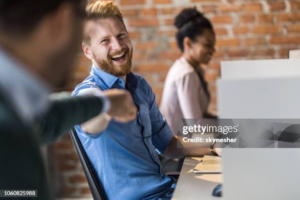 homme d’affaires rousse joyeuse donnant son collègue bosse poing au bureau. - fist bump photos et images de collection