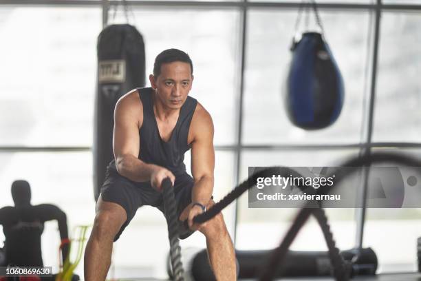 atleta de hacer ejercicio con batalla cuerdas en gimnasia - filipino fotografías e imágenes de stock