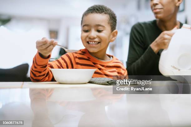 happy boy eating breakfast cereal - boy eating cereal stock pictures, royalty-free photos & images
