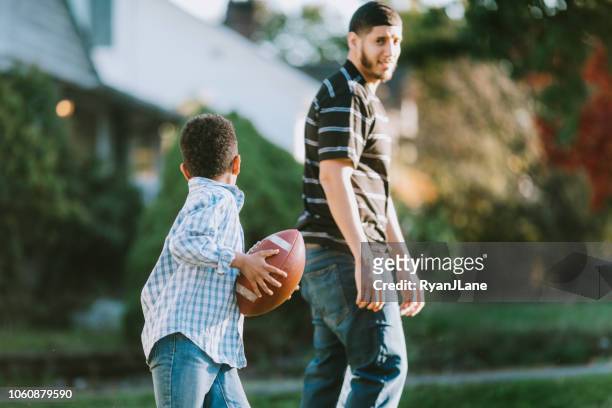 father plays football outside with his son - throwing football stock pictures, royalty-free photos & images