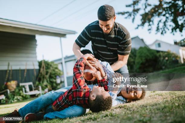 vader speelt voetbal buiten met zijn zonen - tackle stockfoto's en -beelden