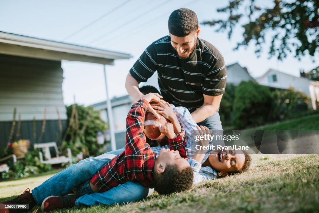 Pai joga futebol lá fora com seus filhos