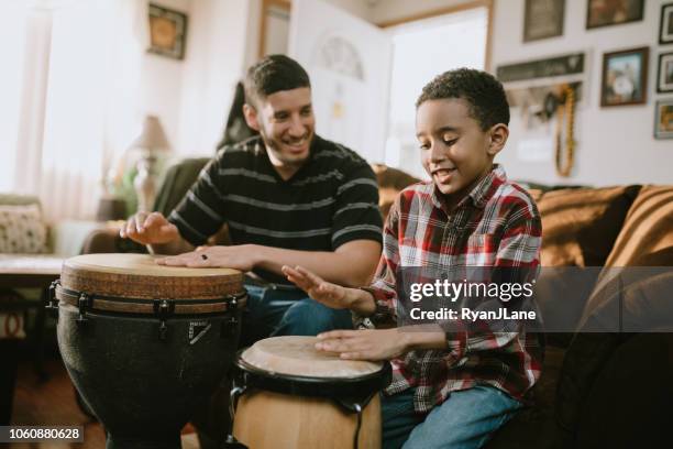 vater lehrt kind spielen handtrommel - vater sohn musik stock-fotos und bilder