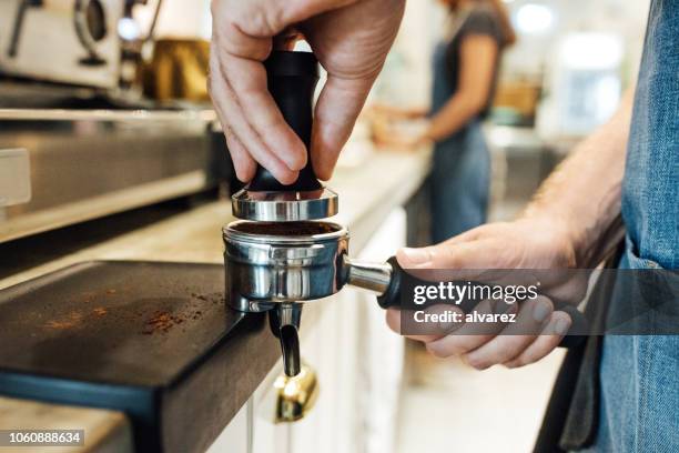 machen einen espresso kaffee mit tamper barista - coffee grinder stock-fotos und bilder