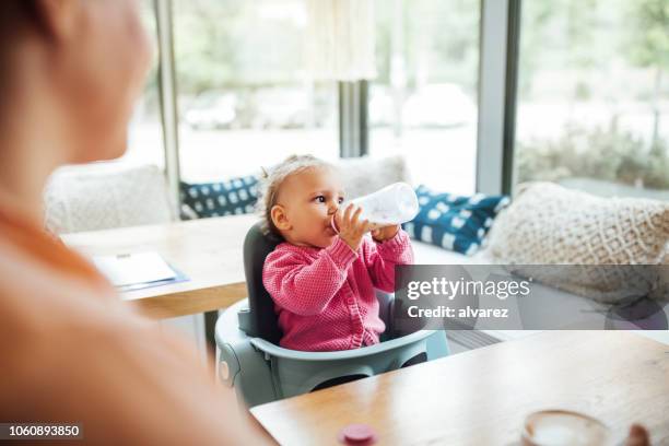 美しい女の赤ちゃんのミルクを飲む赤ちゃんカフェで - baby bottle ストックフォトと画像