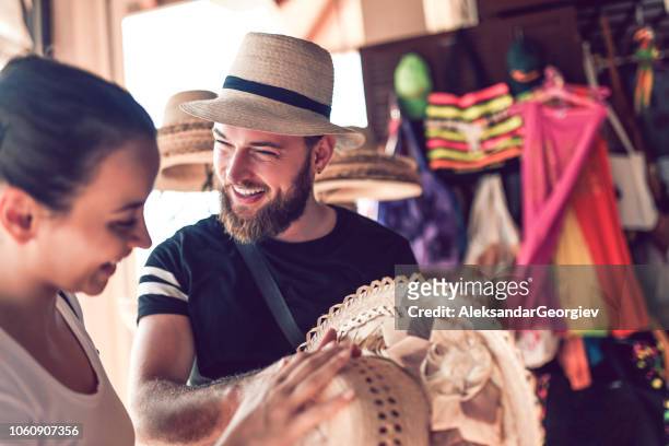 bearded market vendor offering hat to a lady - tourist shopping stock pictures, royalty-free photos & images