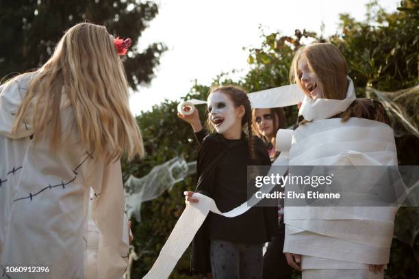 group of older children playing 'wrap the mummy' halloween game with toilet rolls - wrapped in toilet paper stock-fotos und bilder