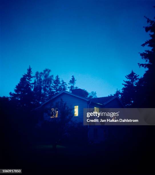 house at dusk with illuminated windows - haunted house stock-fotos und bilder