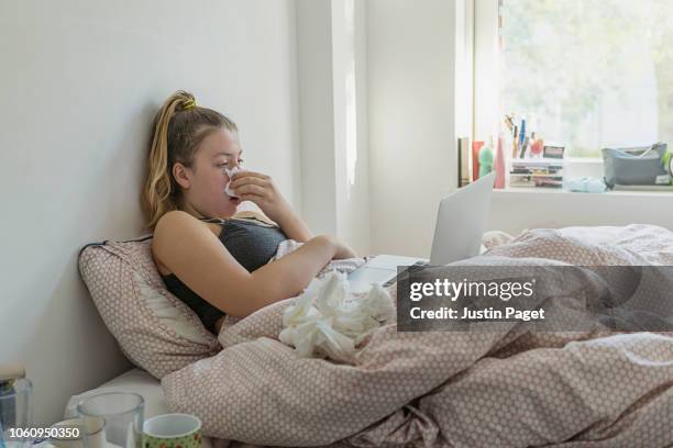 teenage girl in bed with the flu - someone blowing nose stock pictures, royalty-free photos & images
