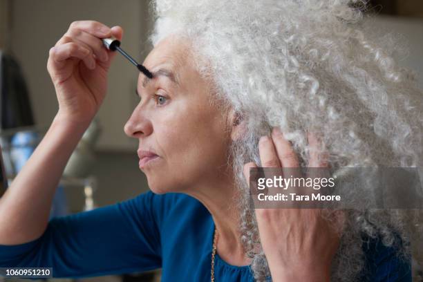 senior woman applying makeup - woman gray hair mirror stock pictures, royalty-free photos & images