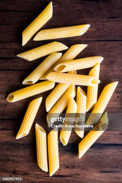 heap of uncooked whole wheat penne italian pasta, top view. pasta pattern. food background. - penne imagens e fotografias de stock