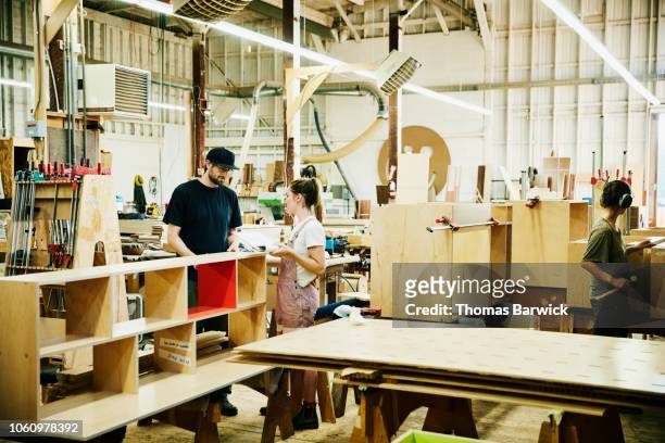 Coworkers discussing building plans while working in cabinet shop