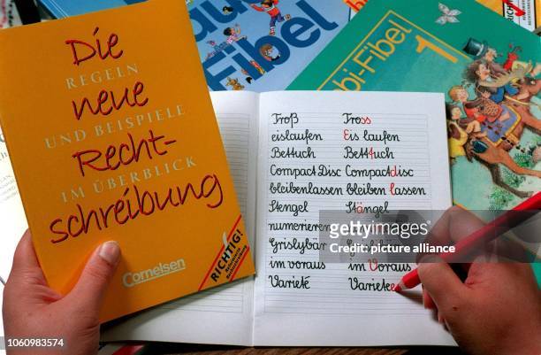 Blick in ein Schulheft mit der alten und neuen Schreibweise verschiedener deutscher Wörter und ein Nachschlagewerk mit den Regeln für die neue,...