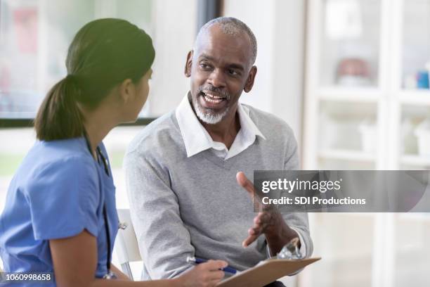 senior man talking with young female nurse - nurse listening to patient stock pictures, royalty-free photos & images