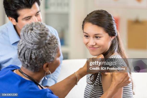 brave teenage girl smiles after vaccination - applying bandage stock pictures, royalty-free photos & images