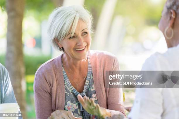 a beautiful senior woman laughs with her friends - sharing stories stock pictures, royalty-free photos & images