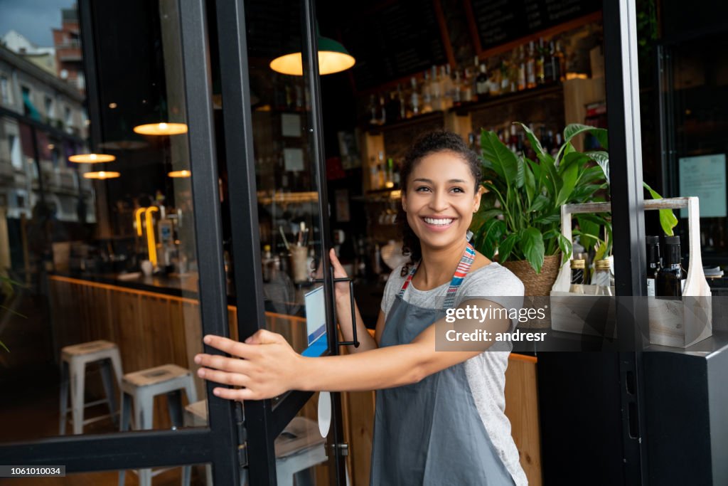 Happy business owner opening the door at a cafe