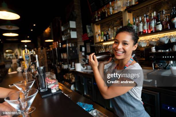 feliz bartender mezcla bebidas en el bar - female bartender fotografías e imágenes de stock