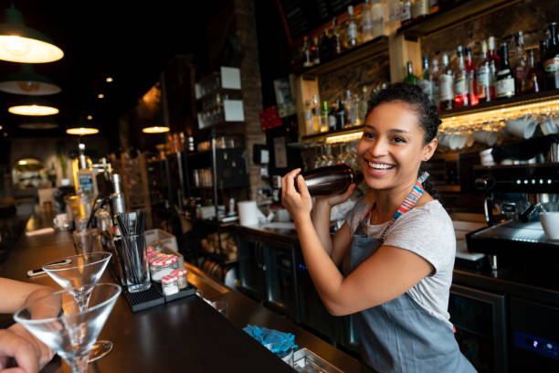 happy bartender mixing drinks at the bar - bartender stock pictures, royalty-free photos & images