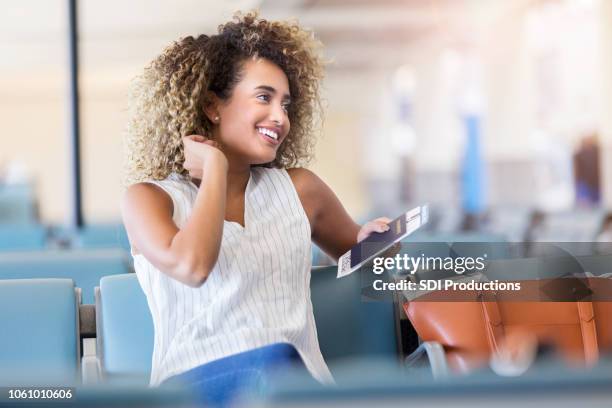 mujer joven utiliza su teléfono celular mientras ella espera para su vuelo - portraits of people passport fotografías e imágenes de stock