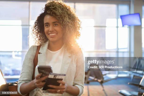 young woman stands expectantly in airport departure area - portraits of people passport stock pictures, royalty-free photos & images