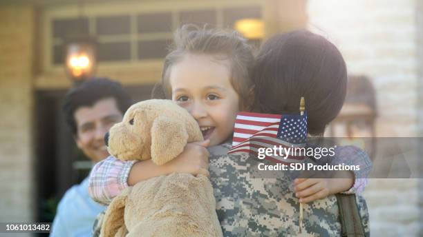 little girl is lifted into hug by a young adult female in uniform - army wife stock pictures, royalty-free photos & images