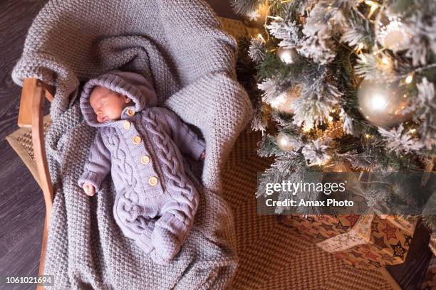 babyjongen slapen onder de kerstboom op new year's eve - december stockfoto's en -beelden