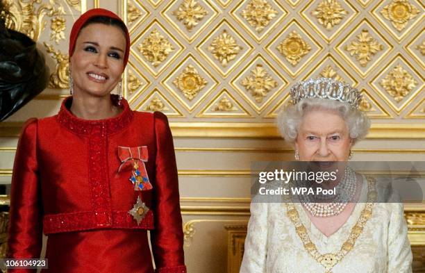 Queen Elizabeth II poses with Sheikha Mozah bint Nasser Al Missned, the wife of Qatar's Emir Sheikh Hamad bin Khalifa al Thani, before a banquet held...