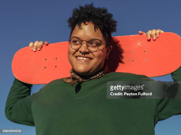smiling woman with orange skateboard - showus stock pictures, royalty-free photos & images