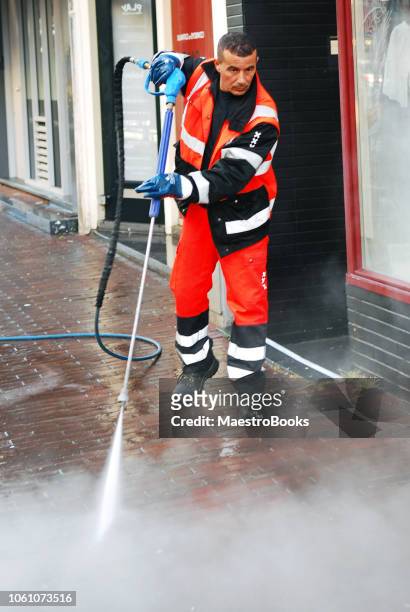 man cleaning graffiti from the streets using a pressure water pump. - cleaning graffiti stock pictures, royalty-free photos & images