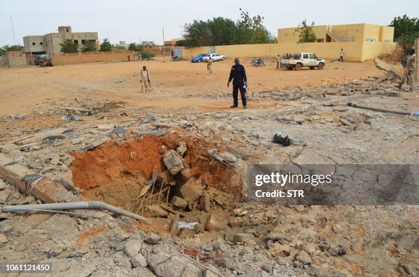 Malian soldiers stand near a hole in the ground caused by the explosion of a suicide car bomb attack overnight, which killed three people, on...