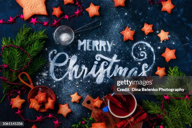 christmas and new year holiday flat lay with traditional baking, star-shaped cookies, sugar powder, flour, and decorations. food lettering concept fon a snowy dark background - flour christmas stockfoto's en -beelden