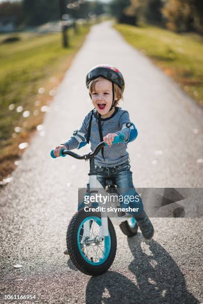 cheerful little boy shouting while riding bicycle in the park. - kids on bikes stock pictures, royalty-free photos & images