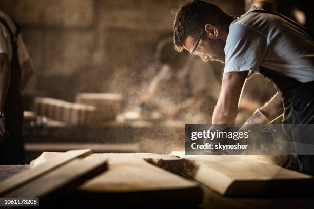 jeune menuisier utilisation ponceuse alors qu’il travaillait sur un morceau de bois. - réparateur photos et images de collection