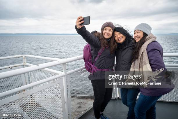 winter travel on ferry, mother and teen daughters taking selfie - british columbia winter stock pictures, royalty-free photos & images