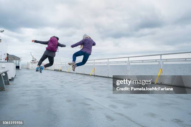 teenaged sisters jumping in unison on ferry deck, canada - offbeat imagens e fotografias de stock